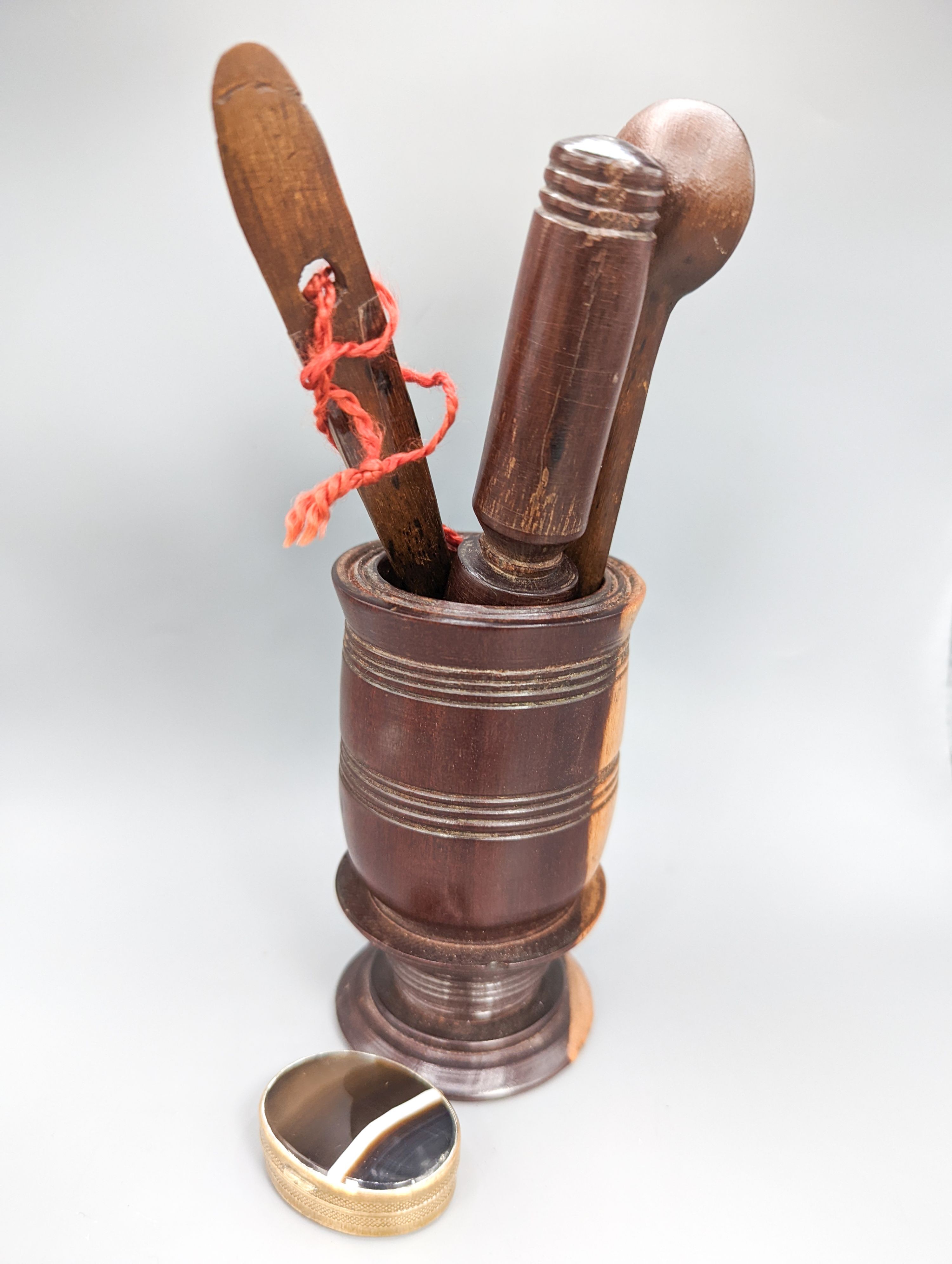 A 19th century lignum vitae pestle and mortar, 10.5cm, a pair of treen butter spoons and an agate mounted brass pillbox